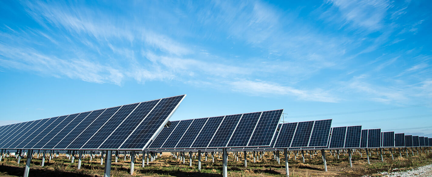 Side view of rows of solar panels under a clear blue sky.
